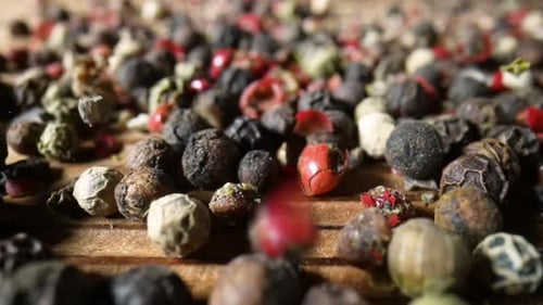 Colorful Medley of Fresh Peppercorns Falling on Wood
