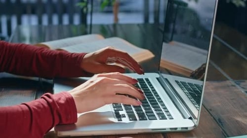 Happy Young Woman Sits with Phone and Computer at the Table