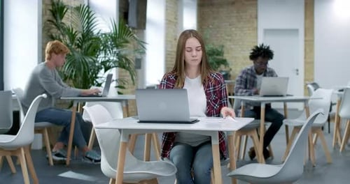 Young Millennial Woman Sitting in Office and Working at Laptop Online. Portrait of Happy Caucasian