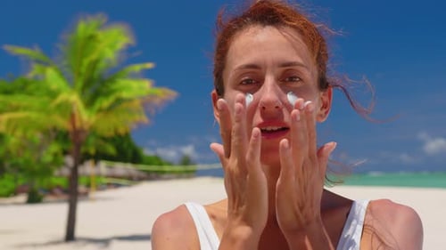 A Woman Passes Sunscreen on Face on a Sunny Day