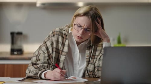 The Woman Works Remotely From Home Sitting at a Table with a Laptop and a Felttip Pen Marks the Data