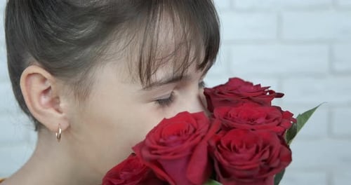Child Smelling Bouquet of Red Roses Smiling