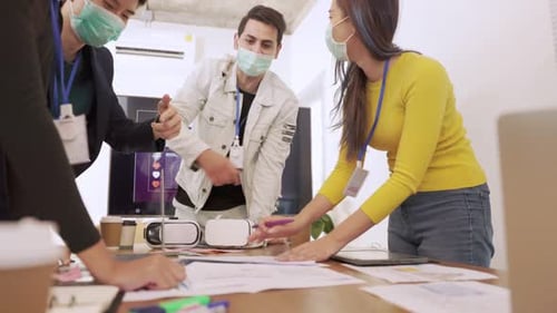 Young people with face masks back at work in office after lockdown