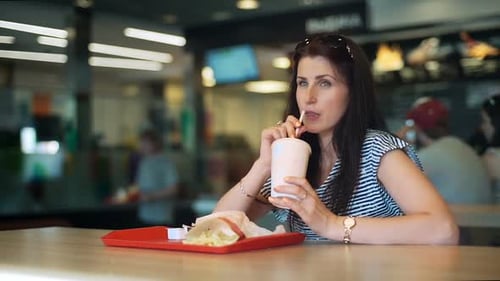 Young Women Eating Fast Food and Drinkink Milk Cocktail