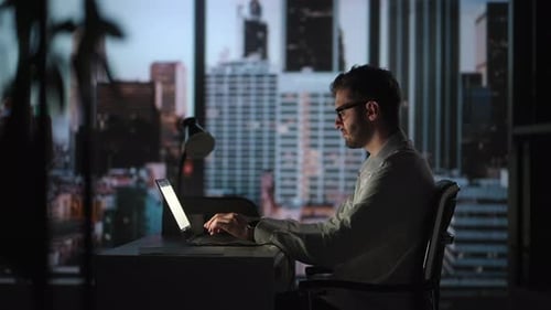 Man Working Late on Laptop in City Office
