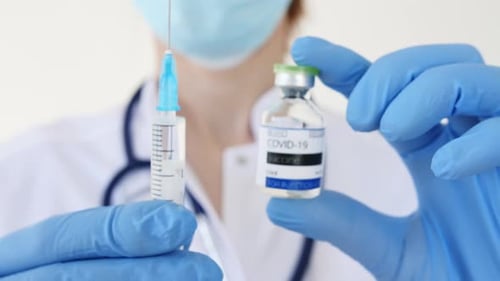 COVID19 Vaccine in Researcher Hands Doctor's Hand Holds a Syringe and a Vaccine Bottle at the