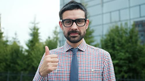Happy Successful Businessman Showing Thumbs-up Gesture Smiling in Modern City
