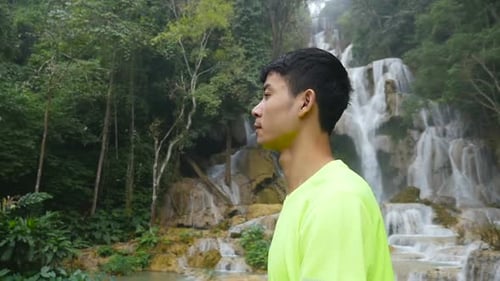 Young Man Near a Tropical Waterfall