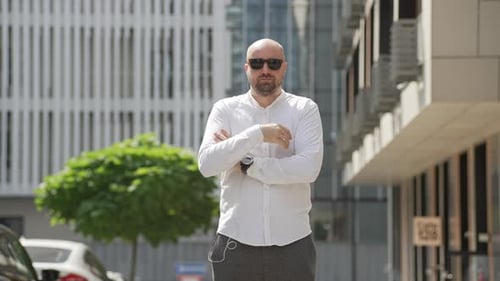 Man Takes Off Sunglasses in Front of Building