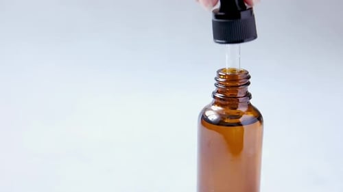 Brown Bottle with Dropper on White Surface
