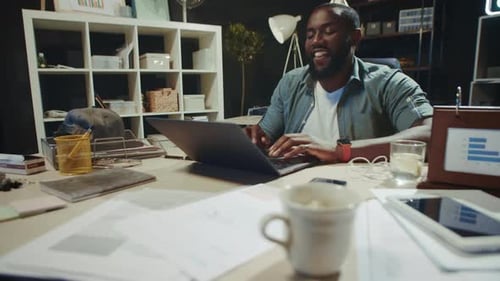 Cheerful African American Businessman Communicating on Laptop in Hipster Office