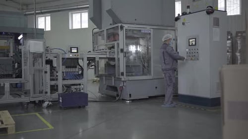 Factory Worker Controls Industrial Machine in Bright Facility