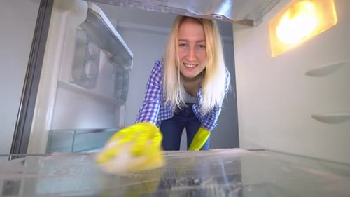 Woman Cleans Refrigerator Shelf from Inside View