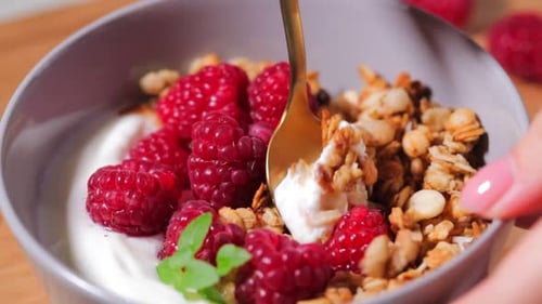 Mixing Granola, Yogurt, and Raspberries in Bowl