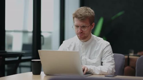 Young Adult Typing on Laptop in Modern Workplace