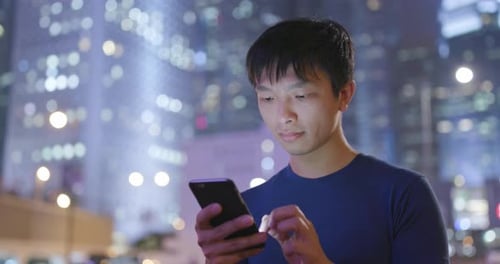 Man use of mobile phone in city at night