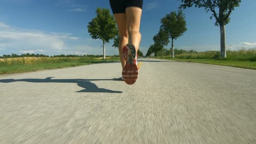 Woman Runs on Rural Road in Sunny Day
