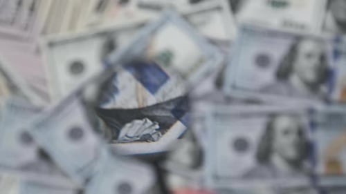 Magnifying Glass Inspecting Pile of Hundred Dollar Bills