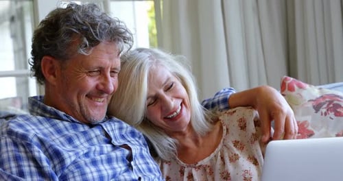 Happy Mature Couple Laughing While Using Laptop