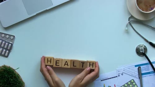 Hands Spelling Health with Blocks in Doctor's Office