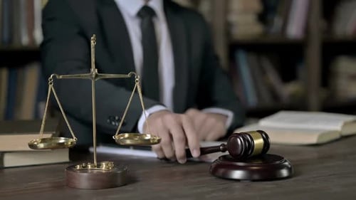 Primer plano de la mano del juez golpeando el mazo en la mesa de la sala de la corte