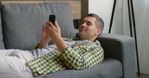 Man Relaxing on Couch with Cell Phone