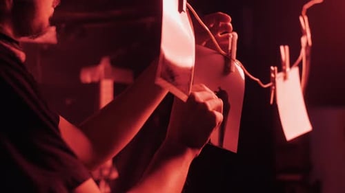 Adult Hanging Developed Photos on Clothesline in Darkroom