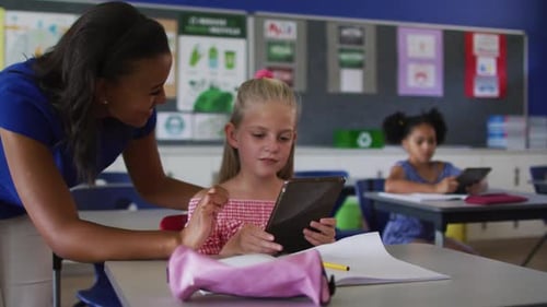 Teacher Helping Student with Tablet in Classroom