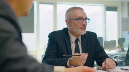 Senior Businessman Talking to Colleagues at Office Meeting