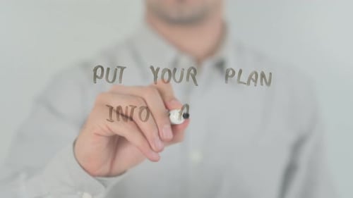 Man Writes Put Your Plan Into Action on Glass