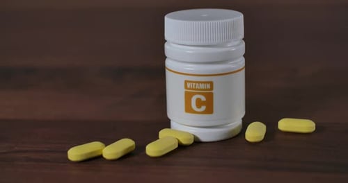 Vitamin C Tablets and Bottle on Wooden Surface