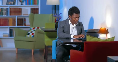 Male African Student Working on Laptop in Library