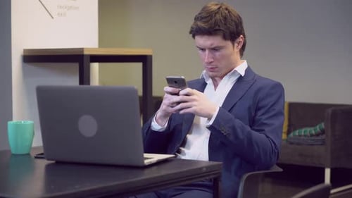 Focused Man Uses Phone in Modern Office