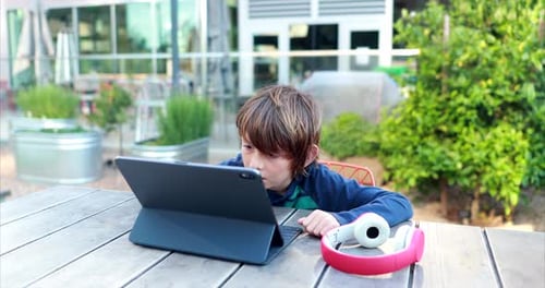 A young boy attempts to learn remotely on his laptop and headphones over distance learning due to th