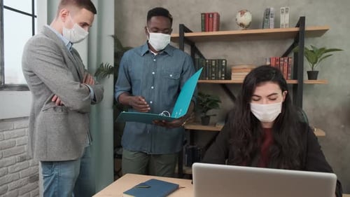 Coworkers Reviewing Documents in Office Wearing Masks