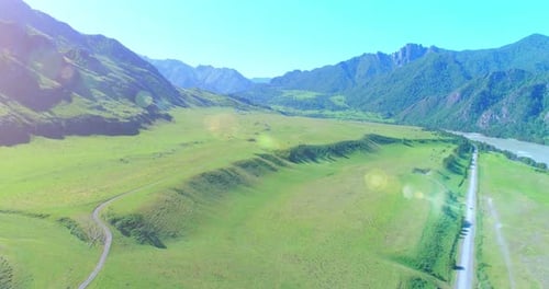 Aerial Rural Mountain Road and Meadow at Sunny Summer Morning. Asphalt Highway and River