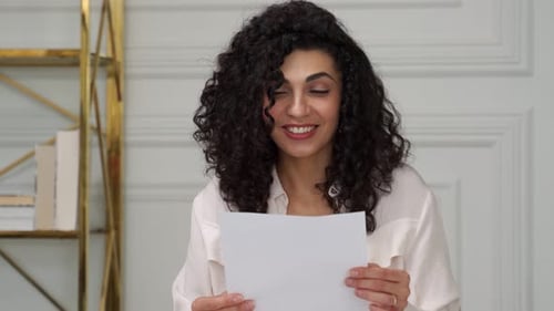 Smiling Woman Reading a Paper Indoors