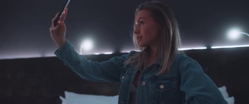 Young Woman Using Cellphone in Dark Bedroom