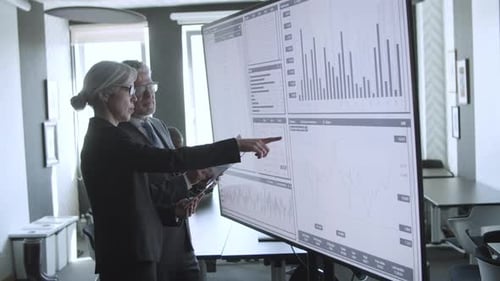 Business Colleagues Review Data on Large Screen