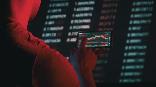 Un trader analyse les graphiques de crypto-monnaie sur l'écran d'un smartphone dans le noir