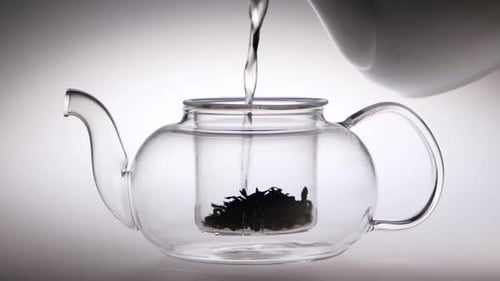 Water Pouring into Crystal Glass Teapot with Tea