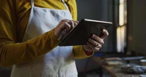 Mittelteil einer kaukasischen Juwelierin in Werkstatt mit Schürze, mit Tablet