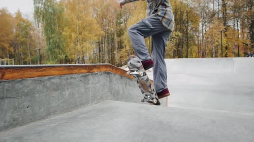 Skater Practicing in the Autumn Concrete Skate Park Making Tricks and Rides in Ramp