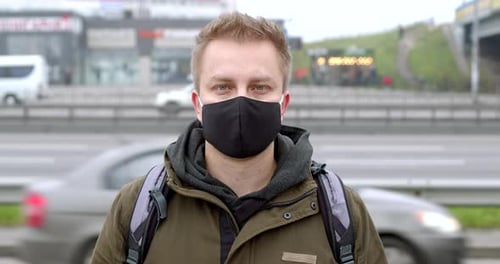 Man Wearing Mask in City with Cars Passing
