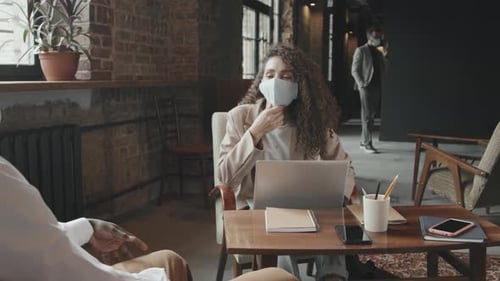 Woman Wearing Mask Works on Laptop in Office
