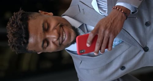 Smiling Young Man Using a Red Smartphone