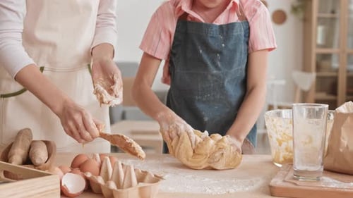 Unrecognizable Girl and Her Mother Kneading Dough