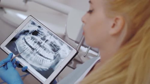 Zahnarzt und Patient wählen Behandlung in einer Beratung mit medizinischen Geräten im Hintergrund