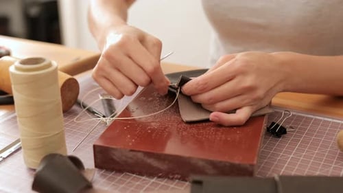 Woman Hand Stitching Leather in her Workshop
