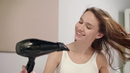 Woman Dries Her Hair with a Hair Dryer